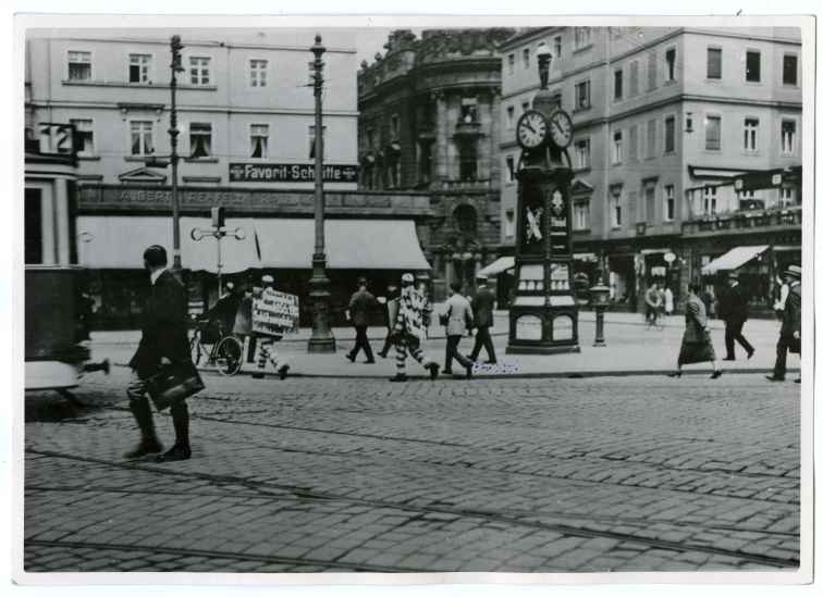 Pirnaischer Platz. Kampagne zur Befreiung von Sacco und Vanzetti, 1927. Menschen eilen über den Platz und schauen zu zwei Männern, die sich Pappschilder um die Schultern gehängt haben. Den Text kann man nicht lesen.  